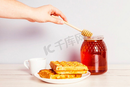 人的手用勺从罐子里摘蜂蜜早餐
