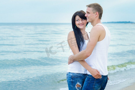t天空摄影照片_男孩和一个女孩在牛仔裤和白色T恤在海边