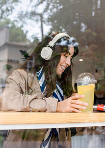 配有新鲜柠檬水耳机的女子咖啡馆
