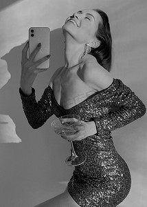 奢华香槟摄影照片_一名年轻女子手持香槟的手机照片。移动内容。用手机拍的照片。新年和聚会