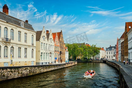 比利时摄影照片_在古老的房子之间的运河上的旅游船。比利时布鲁日。运河里的观光船。布鲁日，比利时