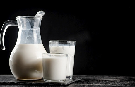牛奶放在桌子上的罐子里。黑色背景。高质量的照片。牛奶放在桌子上的罐子里。 