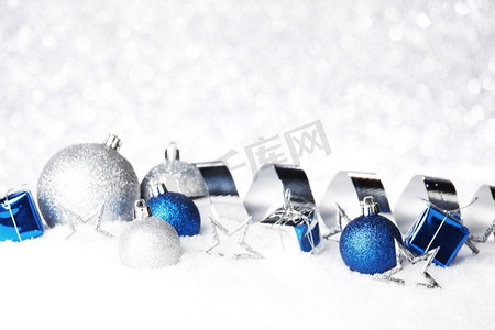 银和蓝色圣诞装饰在雪特写镜头。圣诞节装饰在雪地上