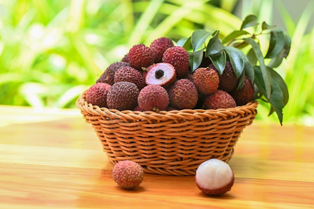 在篮子的荔枝果与绿叶和木背景，新鲜成熟的荔枝从荔枝树剥皮在热带水果泰国在夏天