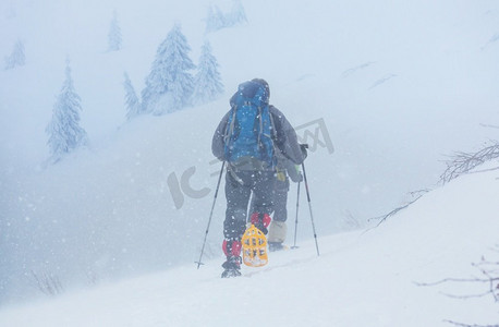 登山徒步的人摄影照片_冬季森林中的徒步旅行者