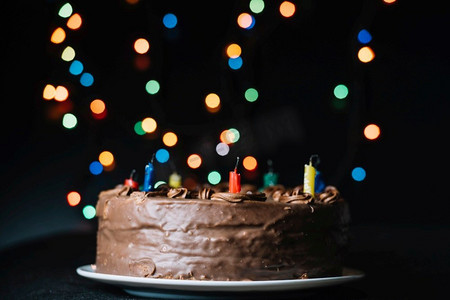 闪光框摄影照片_巧克力蛋糕反对闪光散景灯黑色背景