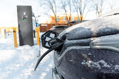 eco摄影照片_车辆、动力和绿色能源概念—电动汽车充电电池在冬季特写镜头。冬季电动汽车充电特写