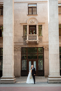 都市家庭摄影照片_在都市气氛中，身穿棕色西装的新郎和穿着白色裙子的新娘
