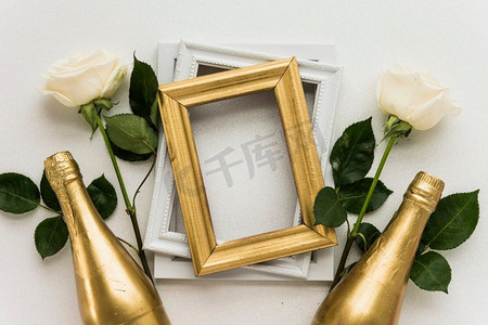 高架视图相框与两个玫瑰香槟瓶白色表面