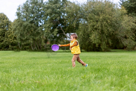 童年、休闲和人的概念-快乐的小男孩在公园里玩飞盘游戏。快乐的小男孩在公园里玩飞碟