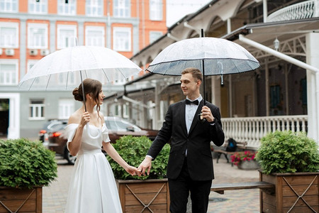 身穿白色短裙的新郎新娘在雨中漫步
