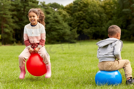 童年，休闲和人的概念—快乐的孩子在公园里跳。快乐的孩子们弹跳在跳球在公园
