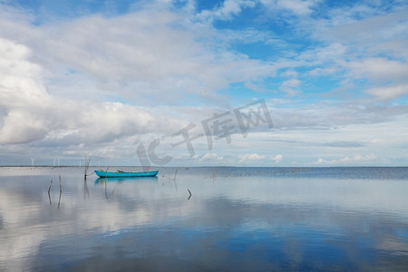 一艘蓝色的小船在蓝色的泻湖里，有着反射的云彩。斯里兰卡、亚洲。