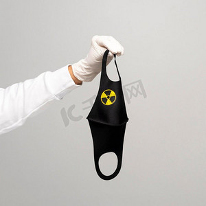 口罩标志摄影照片_戴手套的妇女戴着带有放射性标志的口罩