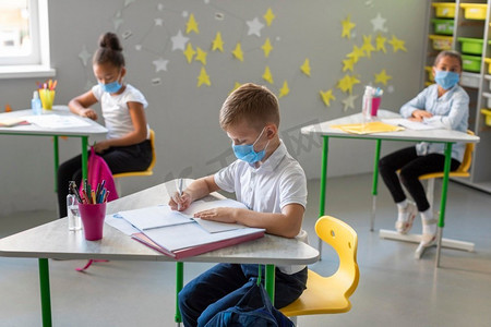 侧面视图孩子们在戴着医用口罩的时候做笔记课堂