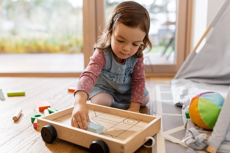童年，hygge和人的概念—小女婴在家里玩玩具块。快乐的女婴玩玩具块在家里