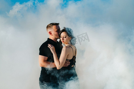 男孩和一个女孩在黑色的衣服拥抱在一个白色的烟雾