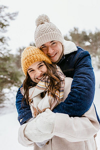 隔空拥抱摄影照片_人，爱和休闲概念—愉快的微笑夫妇拥抱在冬季公园。愉快的微笑夫妇拥抱在冬季公园