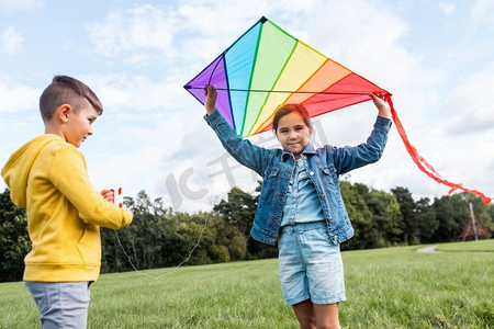 童年，休闲和人的概念—快乐的男孩和女孩与风筝在公园玩。快乐的男孩和女孩与风筝玩在公园