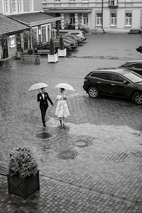 年轻夫妇新娘和新郎在一个白色短礼服走在雨中