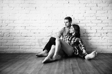 一个男孩和女孩坐在地板附近的白色砖墙