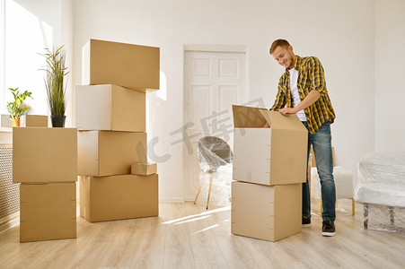 男人在大量的纸箱里装东西。搬到新房子或公寓。男人在很多箱子里装东西