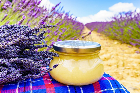 在新鲜的薰衣草田野背景下放入蜂蜜的罐子。法国的普罗旺斯..盛放蜂蜜和薰衣草花的罐子。