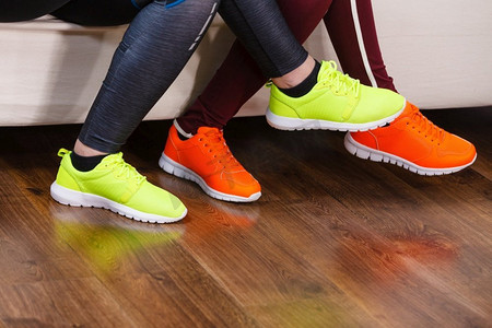 两个不知名的女人穿着运动鞋，红色和霓虹绿的。锻炼装备件..两双运动鞋