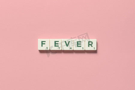 发烧字形成的拼字游戏块在粉红色背景。危险疾病和身体健康意识。由拼字游戏块形成的发烧。
