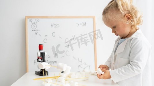 侧面视图可爱的蹒跚学步的学习关于科学与白板显微镜