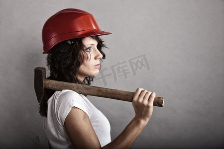性别平等和女权主义。性感女孩戴着安全帽拿着锤子工具。做建筑工人的漂亮女人。