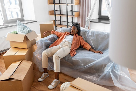 移动，人和房地产概念—疲惫的妇女与盒子睡在沙发在新家。疲惫的女人睡在沙发上移动到新家