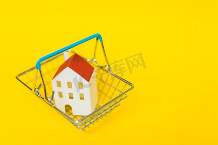 黄色背景框摄影照片_俯视图房子模型在购物车内反对黄色背景