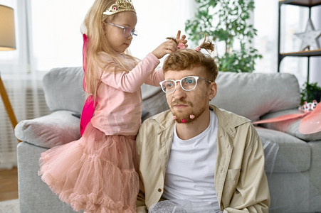 女儿给父亲创造滑稽发型，家庭快乐时刻和父亲的享受。女儿创造有趣的发型给父亲
