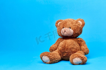 软玩具和童年概念—棕色泰迪熊在蓝色背景。棕色泰迪熊玩具在蓝色背景