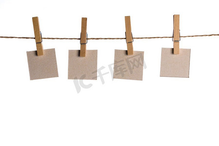 记录文案摄影照片_4注意用木夹或晾衣夹挂在绳子上的挂在白色隔离的纸卡片。在绳子上记录纸卡片