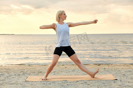 一名女子在海滩上做瑜伽射箭姿势