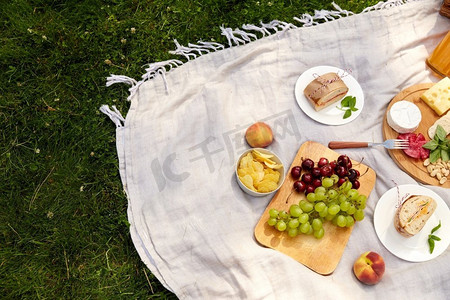 休闲和饮食概念—关闭食物或小吃野餐毯在夏季花园。关闭食物或小吃野餐在花园