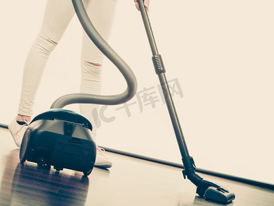 家庭清洁工具和器具，家政职责概念。女人的腿和吸尘器。女人的腿和吸尘器