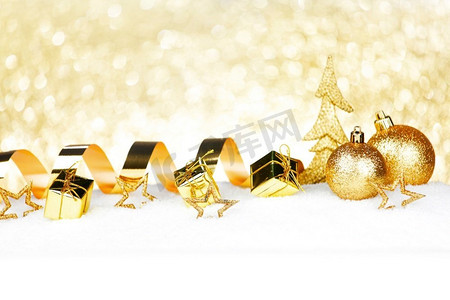 美丽的各种金色圣诞装饰上的雪特写。雪地上的圣诞装饰