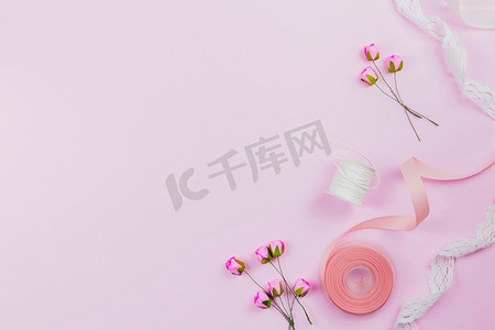 朱砂工艺摄影照片_俯视图人造玫瑰线轴丝带粉红色背景
