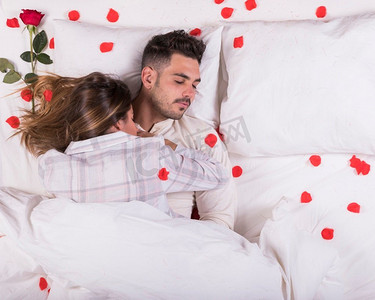 年轻夫妇睡觉的床与玫瑰花瓣