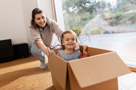 家庭，hygge和人的概念—快乐的母亲和小女儿坐在盒子里玩在家里。快乐的母亲和女儿在盒子里玩在家里