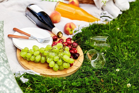 休闲和饮料概念—关闭食物，饮料和篮子野餐毯子在草地上。食物，饮料和篮子野餐毯子在草地上