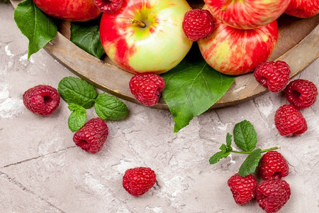 新鲜的乌藨子和苹果在一个具体背景的老木盘子。健康的概念。天然健康食品有机食品。