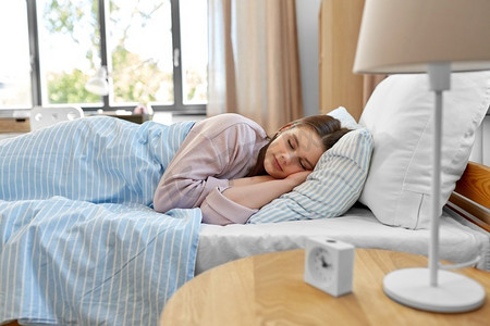 人,就寝时间和休息概念-早上在家里睡在床上的少女.吊带睡衣人物特写