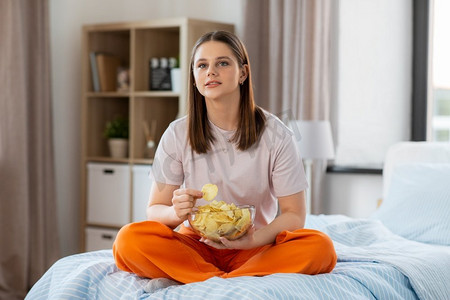 休闲少年美女盘腿床上愉快享用快餐零食