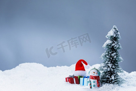 新年或圣诞卡与装饰雪。玩具雪人礼物圣诞老人帽子和冷杉树，复制空间文字。圣诞卡与装饰在雪地上