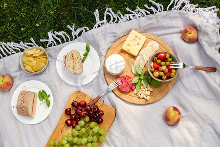 休闲和饮食概念—关闭食物或小吃野餐毯在夏季花园。关闭食物或小吃野餐在花园