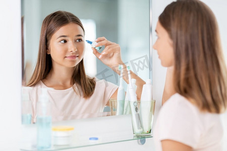 美丽和视觉人概念—十几岁的女孩有眼药水在镜子前在家庭浴室。十几岁的女孩与眼药水在镜子前